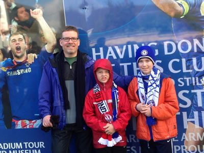 Three people in front of soccer poster